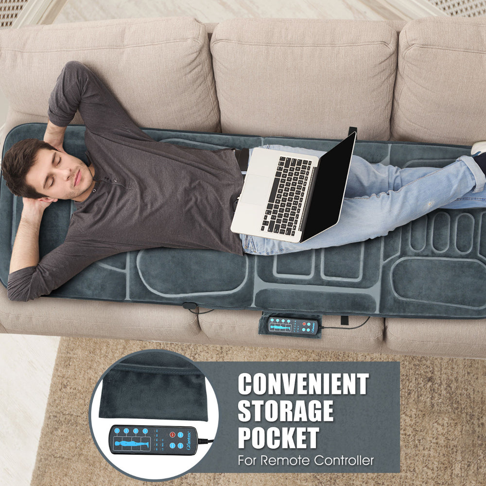 Full-body vibrating massage mat with 10 motors and heat, shown on a sofa with a user relaxing and working on a laptop.