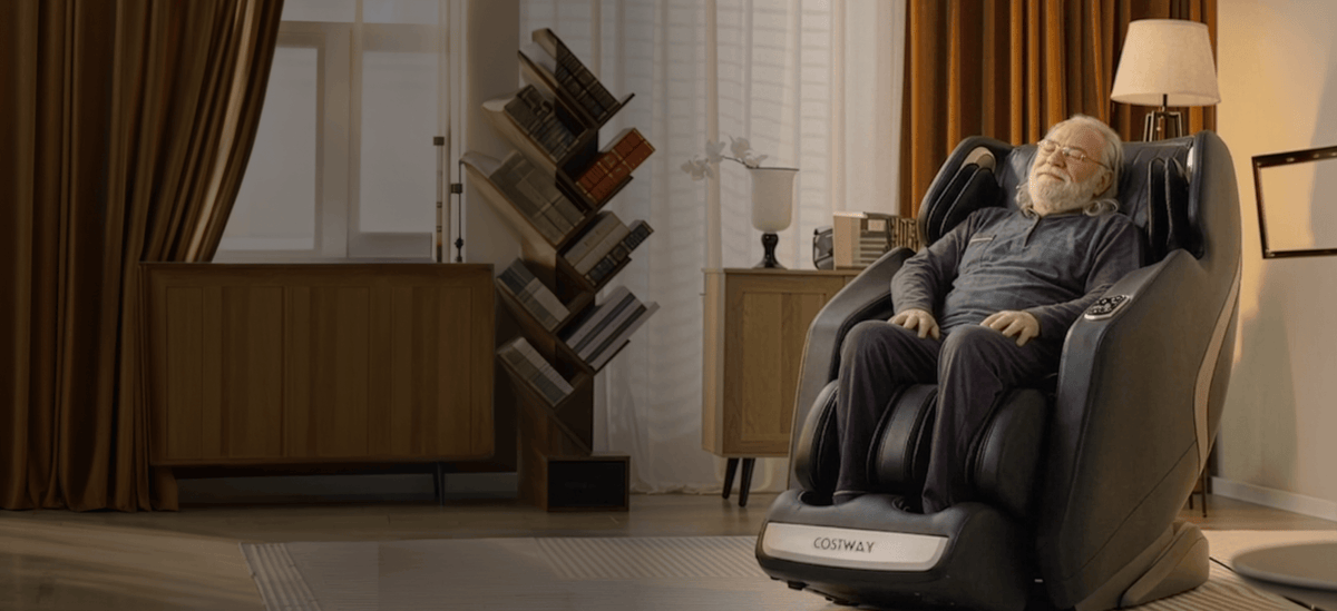 Elderly man relaxing in a black luxury massage chair in a cozy living room.